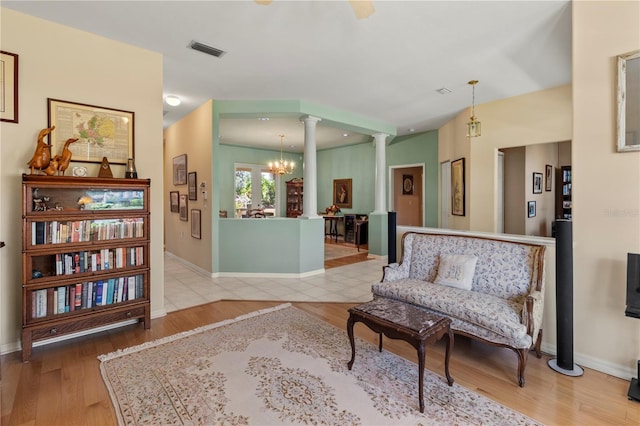 living area with decorative columns, a chandelier, and light hardwood / wood-style flooring