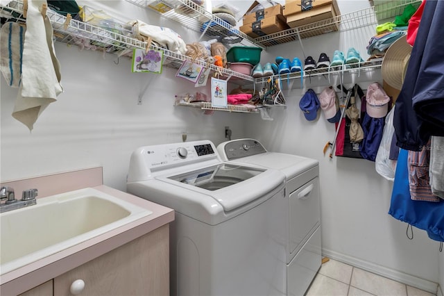 clothes washing area with sink, light tile patterned floors, and washing machine and clothes dryer