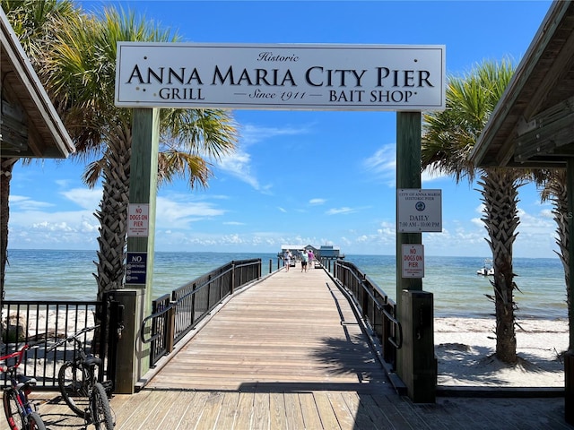 view of dock with a water view and a beach view