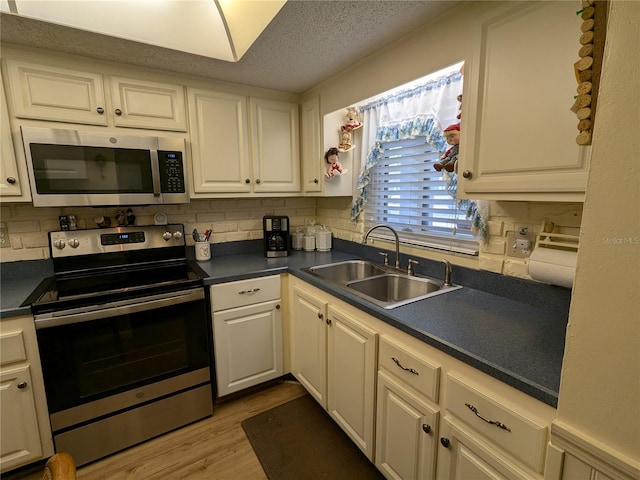 kitchen featuring sink, light wood-type flooring, appliances with stainless steel finishes, and decorative backsplash