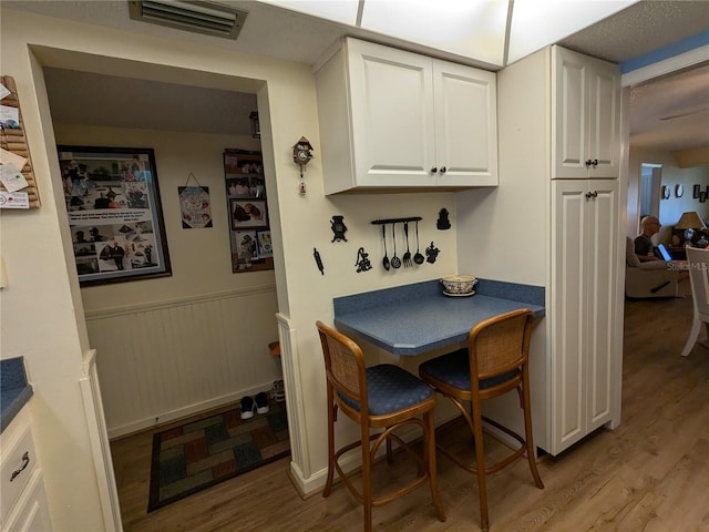 dining area featuring a wainscoted wall, visible vents, and light wood finished floors