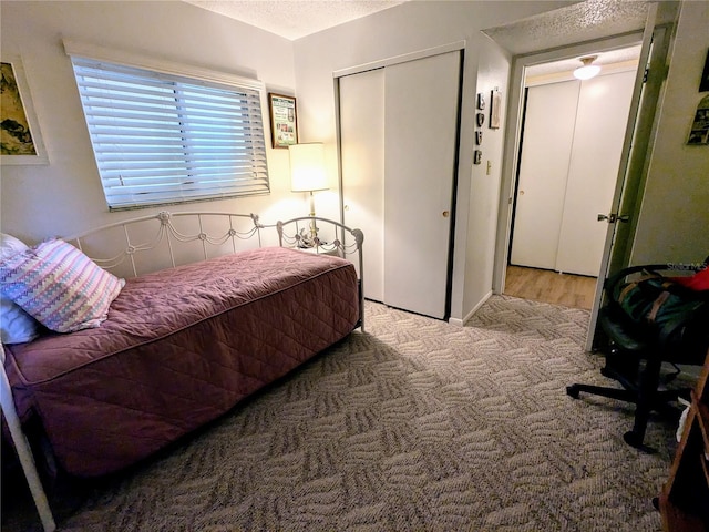 bedroom with a textured ceiling, carpet floors, and a closet