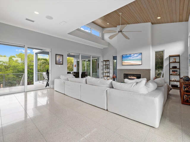 living room with recessed lighting, a towering ceiling, a glass covered fireplace, wood ceiling, and ceiling fan