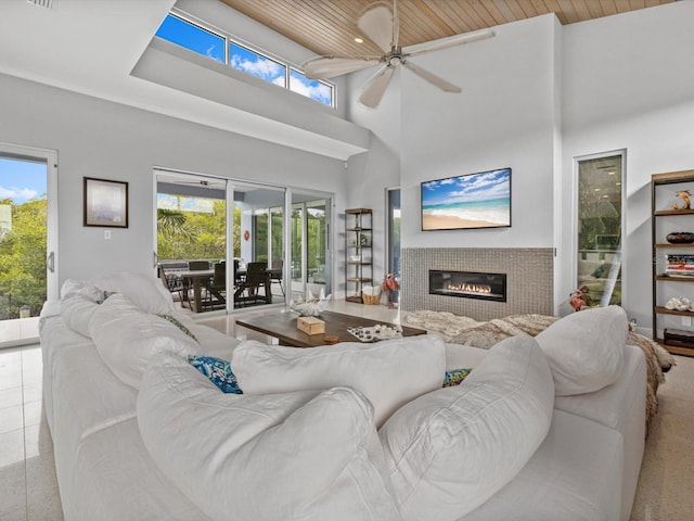 living room with a towering ceiling, wooden ceiling, ceiling fan, tile patterned floors, and a fireplace