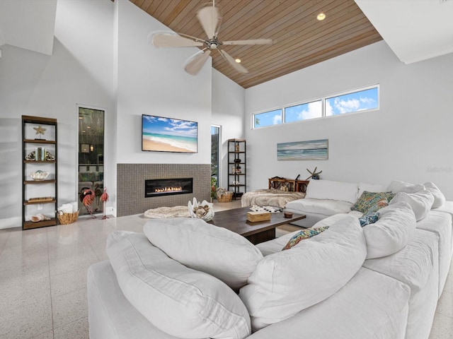 living area with wooden ceiling, a tile fireplace, recessed lighting, a ceiling fan, and a towering ceiling