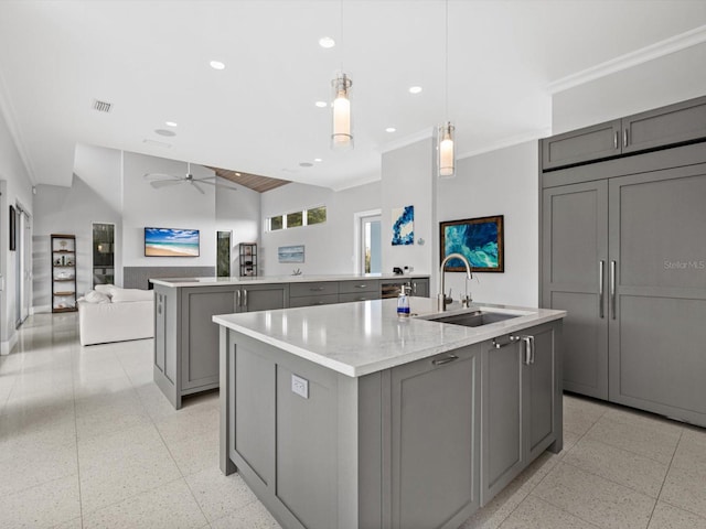 kitchen featuring light speckled floor, gray cabinets, a sink, and a center island with sink