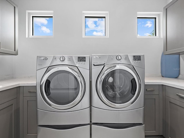 clothes washing area with independent washer and dryer and cabinet space