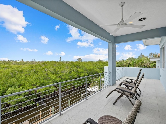 balcony with a ceiling fan and a wooded view