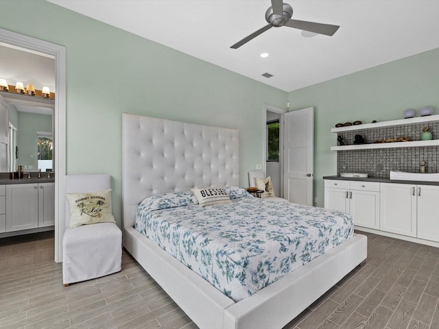 bedroom with visible vents, a ceiling fan, connected bathroom, wood finish floors, and a sink