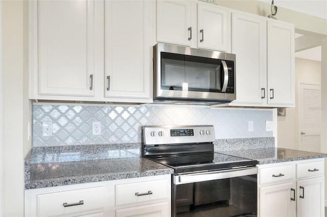 kitchen with dark stone countertops, stainless steel appliances, decorative backsplash, and white cabinetry