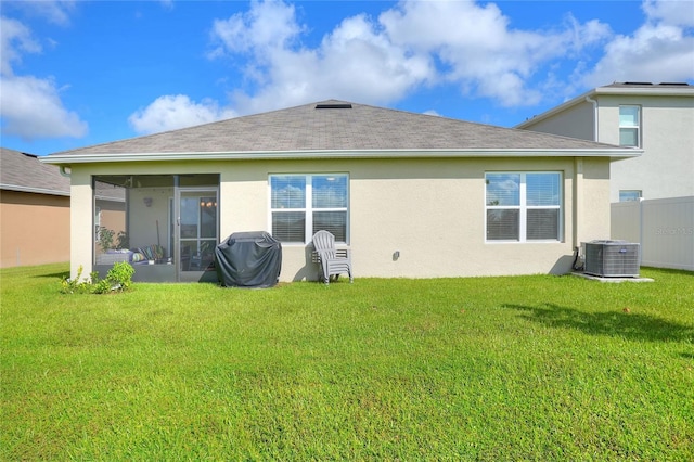 rear view of property featuring cooling unit, a lawn, and a sunroom