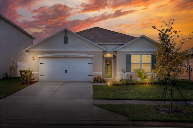 ranch-style home with a garage and a yard