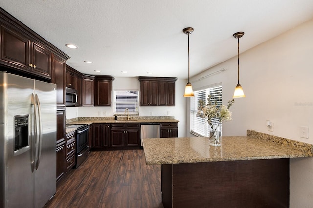 kitchen featuring dark brown cabinets, kitchen peninsula, stainless steel appliances, pendant lighting, and dark wood-type flooring