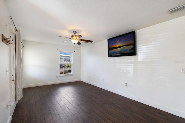 empty room featuring a textured ceiling, dark wood-type flooring, and ceiling fan