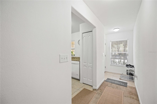 hallway featuring light tile patterned flooring and baseboards