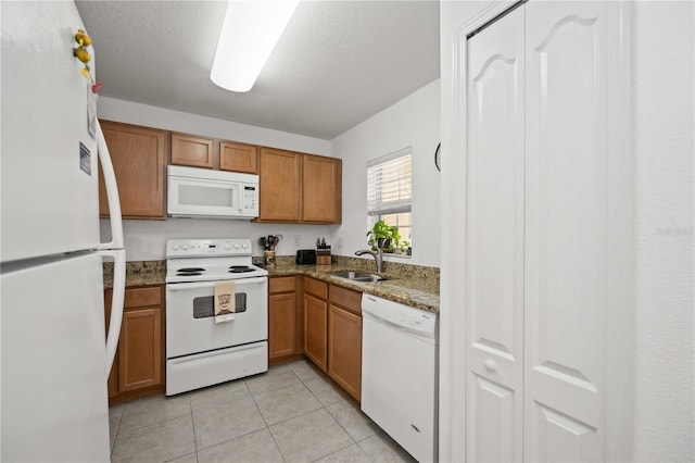10959 Keys Gate Dr, Riverview, FL 33579 - kitchen with white appliances, light tile patterned floors, brown cabinets, a sink, and a textured ceiling