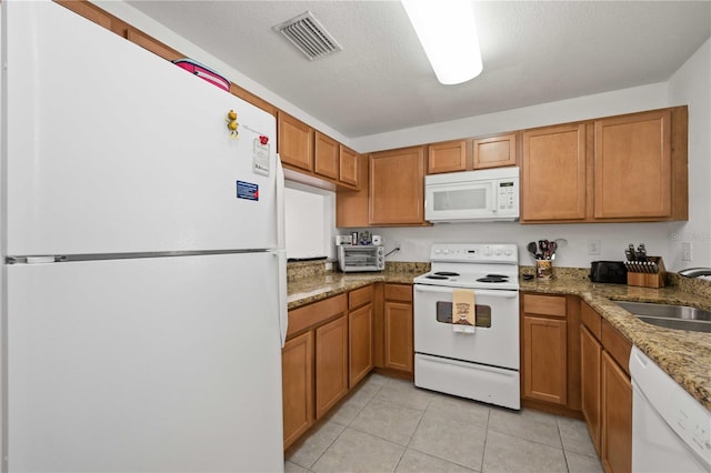 10959 Keys Gate Dr, Riverview, FL 33579 - kitchen with a sink, visible vents, light stone countertops, white appliances, and brown cabinetry