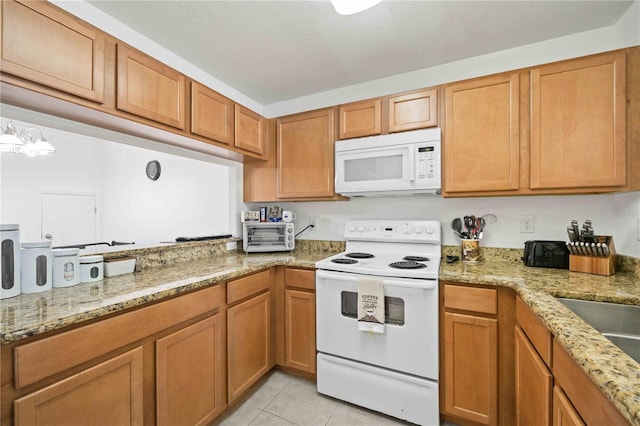 10959 Keys Gate Dr, Riverview, FL 33579 - kitchen featuring light tile patterned floors, brown cabinets, light stone counters, and white appliances