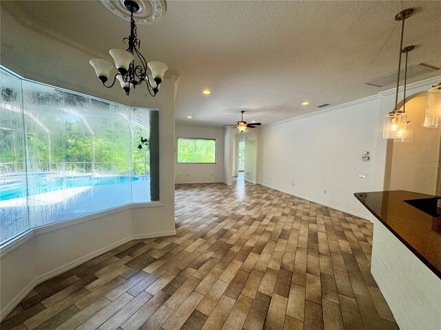 unfurnished dining area featuring recessed lighting, a textured ceiling, wood finished floors, baseboards, and ceiling fan with notable chandelier