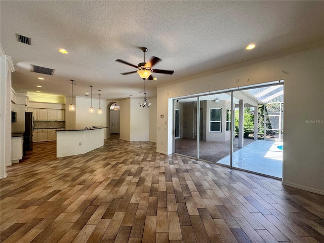 unfurnished living room featuring dark wood-style floors, a textured ceiling, visible vents, and a ceiling fan