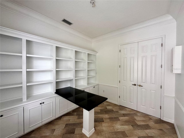 interior space featuring a textured ceiling, visible vents, and crown molding