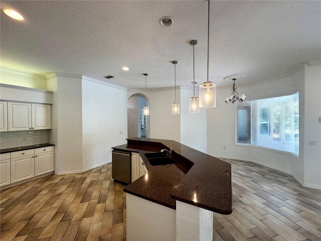 kitchen featuring decorative backsplash, stainless steel dishwasher, ornamental molding, sink, and a center island