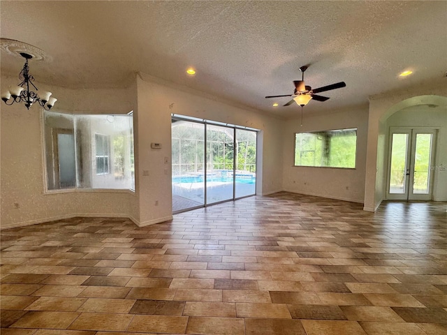 spare room featuring a textured ceiling, french doors, arched walkways, and baseboards