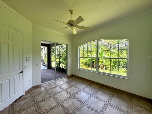 spare room with a ceiling fan, crown molding, a textured ceiling, and baseboards