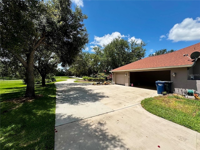 exterior space with a garage, a lawn, concrete driveway, roof with shingles, and stucco siding