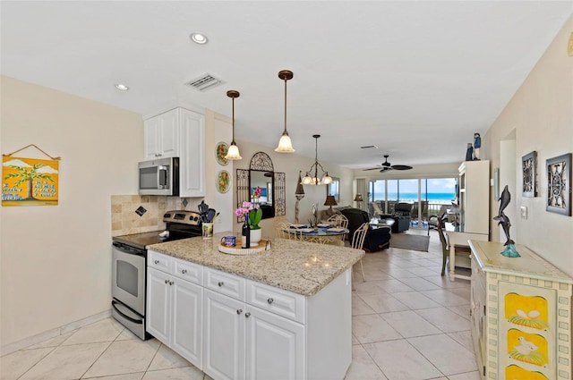 kitchen with visible vents, appliances with stainless steel finishes, open floor plan, light stone countertops, and white cabinetry