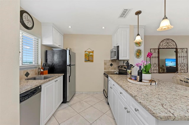 kitchen with light stone counters, appliances with stainless steel finishes, white cabinetry, pendant lighting, and a sink