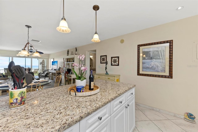 kitchen with light tile patterned floors, light stone counters, decorative light fixtures, and white cabinets