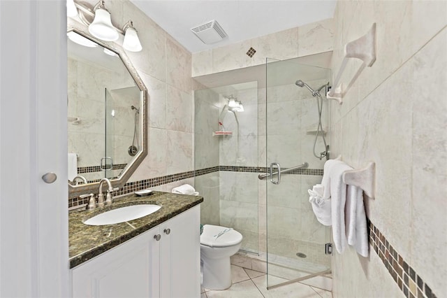 full bathroom with a shower stall, visible vents, tile walls, and vanity