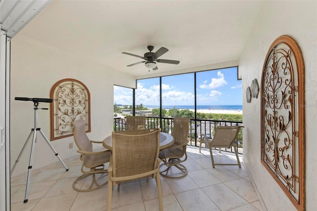 dining room with a water view, light tile patterned floors, expansive windows, and a ceiling fan