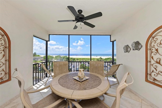 sunroom / solarium with a ceiling fan and a water view