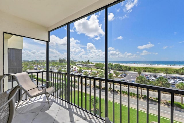 sunroom / solarium featuring a water view, a view of the beach, and lofted ceiling