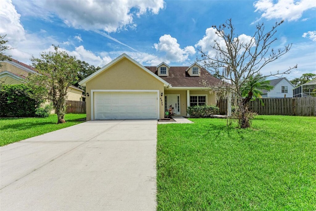 4925 70th St E, Palmetto, FL 34221 - view of front facade with stucco siding, a garage, a front yard, and fence