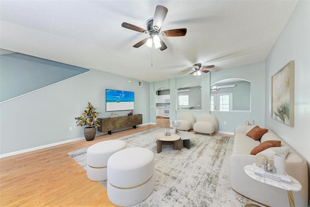 living room with ceiling fan, hardwood / wood-style flooring, and a textured ceiling