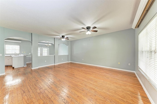 unfurnished living room featuring ceiling fan, light hardwood / wood-style floors, a textured ceiling, and sink