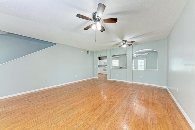 unfurnished living room with a textured ceiling, light hardwood / wood-style flooring, and ceiling fan