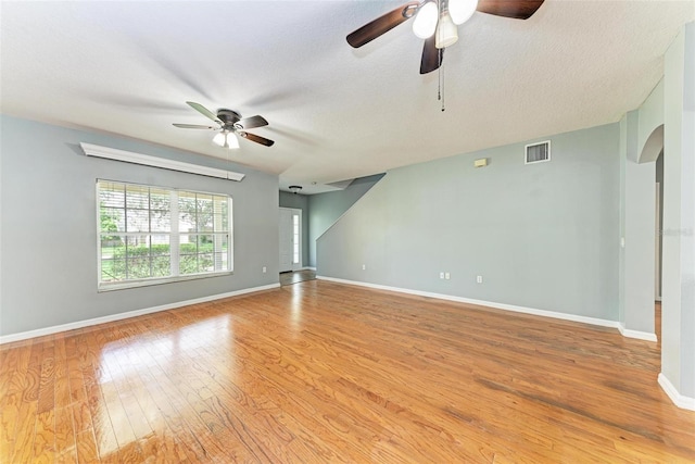 empty room featuring light wood-type flooring, ceiling fan, and a textured ceiling