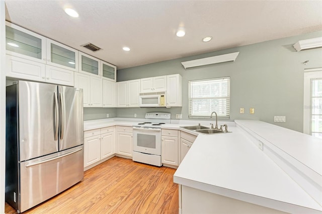 kitchen featuring white appliances, kitchen peninsula, sink, white cabinetry, and light wood-type flooring