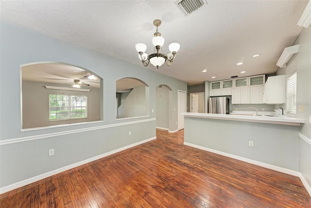 interior space with stainless steel fridge, dark hardwood / wood-style flooring, white cabinetry, and a textured ceiling