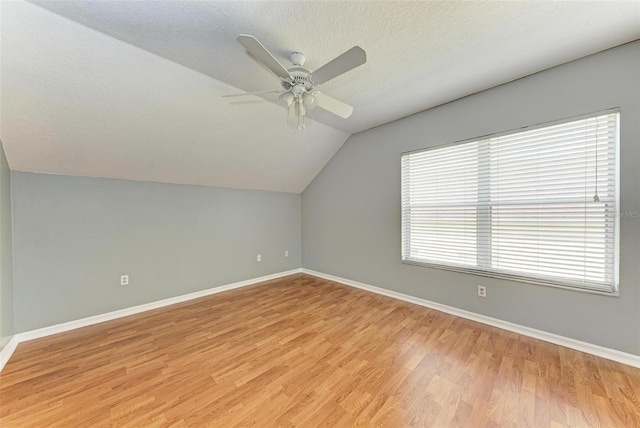 additional living space featuring lofted ceiling, ceiling fan, light hardwood / wood-style floors, and a textured ceiling