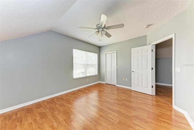 unfurnished bedroom featuring lofted ceiling, ceiling fan, a textured ceiling, and light hardwood / wood-style flooring