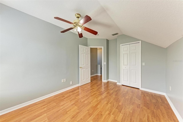 unfurnished bedroom with lofted ceiling, ceiling fan, light hardwood / wood-style floors, and a textured ceiling