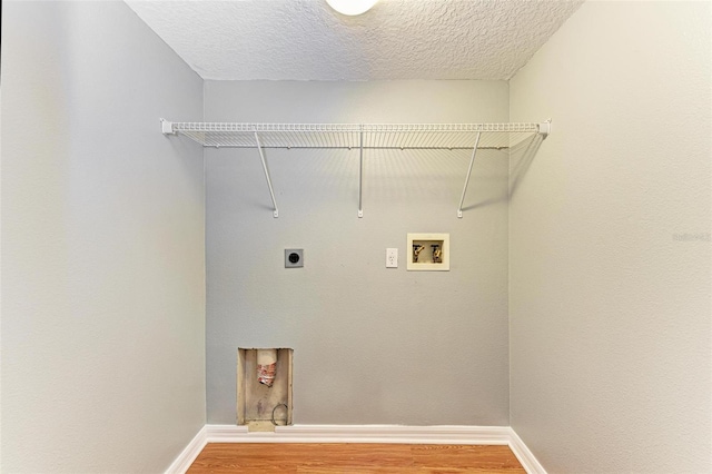 laundry room with hookup for a washing machine, electric dryer hookup, wood-type flooring, and a textured ceiling