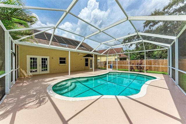 view of pool with glass enclosure, a patio, and french doors