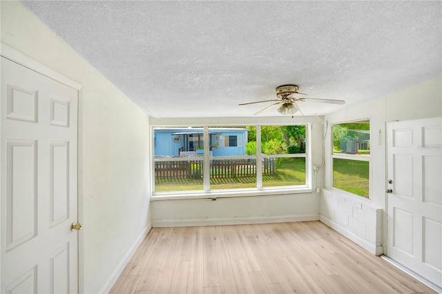 interior space with a wealth of natural light, light hardwood / wood-style floors, and ceiling fan