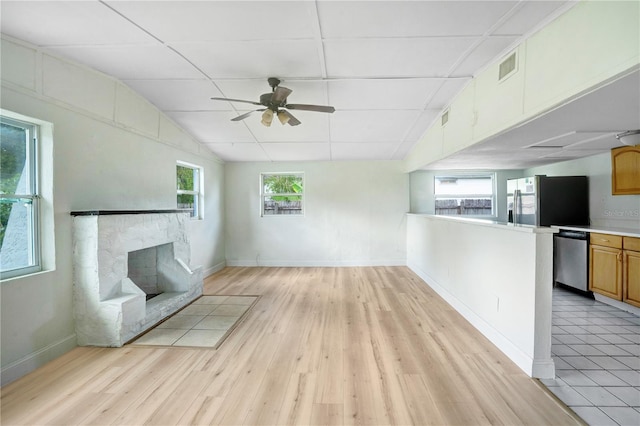 unfurnished living room featuring a wealth of natural light, ceiling fan, light tile patterned floors, and lofted ceiling